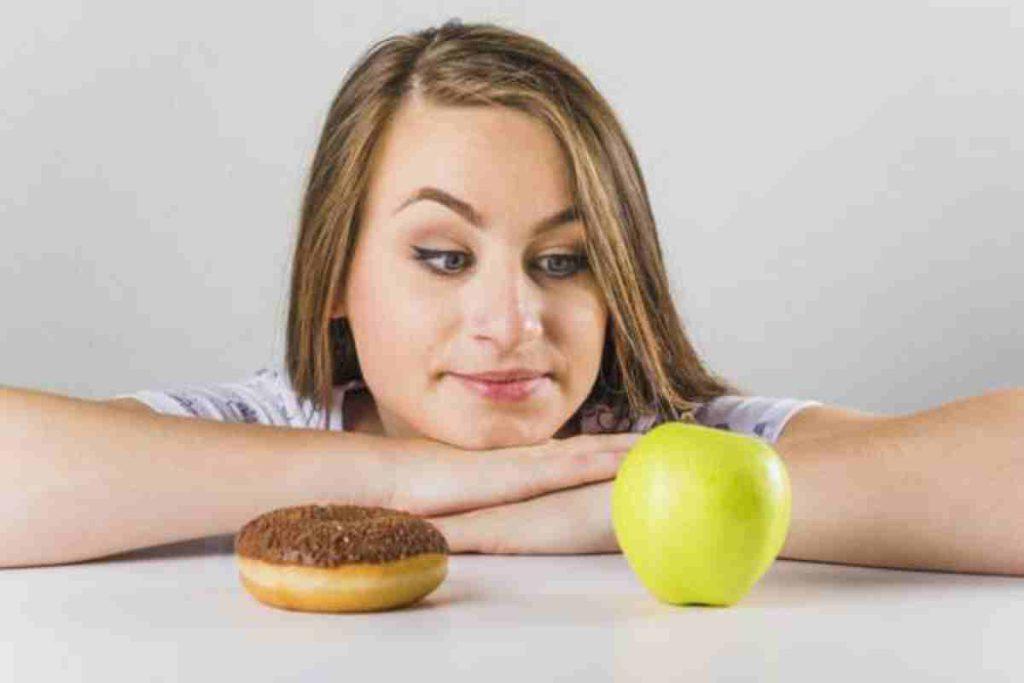 دختری که به سیب را زده و در میز شیرینی و سیب قرار دارد