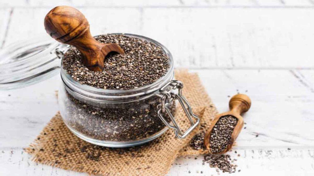 خواص دانه چیا و ژل دانه چیا در رفع التهاب یک ظرف شیشه ای حاوی دانه چیا خام که یک قاشق کوچک چوبی در آن قرار دارد و یک قاشق چوبی کوچک دیگر که پر از دانه چیا خام است در کنار ظرف قرار دارد و خواص دانه جیا برای رفع التهاب را نشان میدهد
