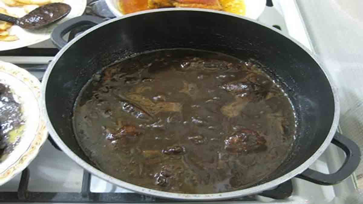 مرحله ششم پخت نهایی فسنجون با مرغ یک قابلمه حاوی خورشت فسنجون با مرغ که بر روی گاز قرار دارد و جوش میخورد و مرحله ششم پخت نهایی فسنجون با مرغ را نشان می دهد